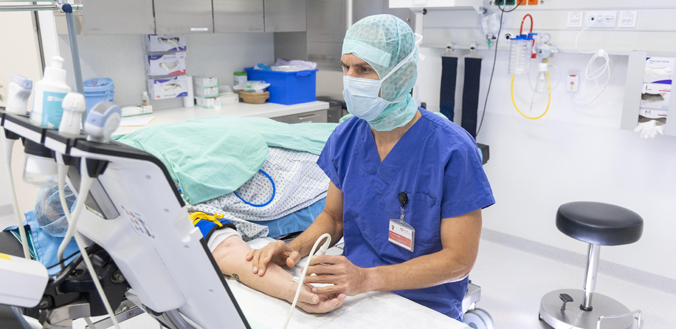Arzt untersucht Hand in einem Behandlungszimmer.