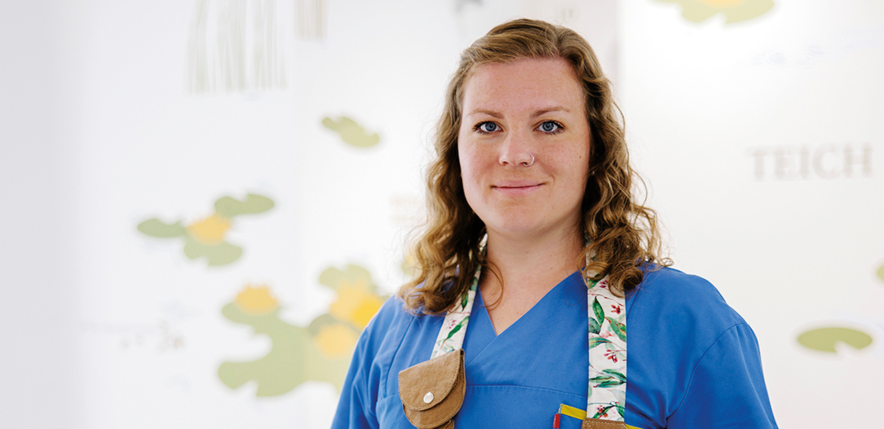 Frau mit blauer Krankenhauskleidung und Fotoapparat