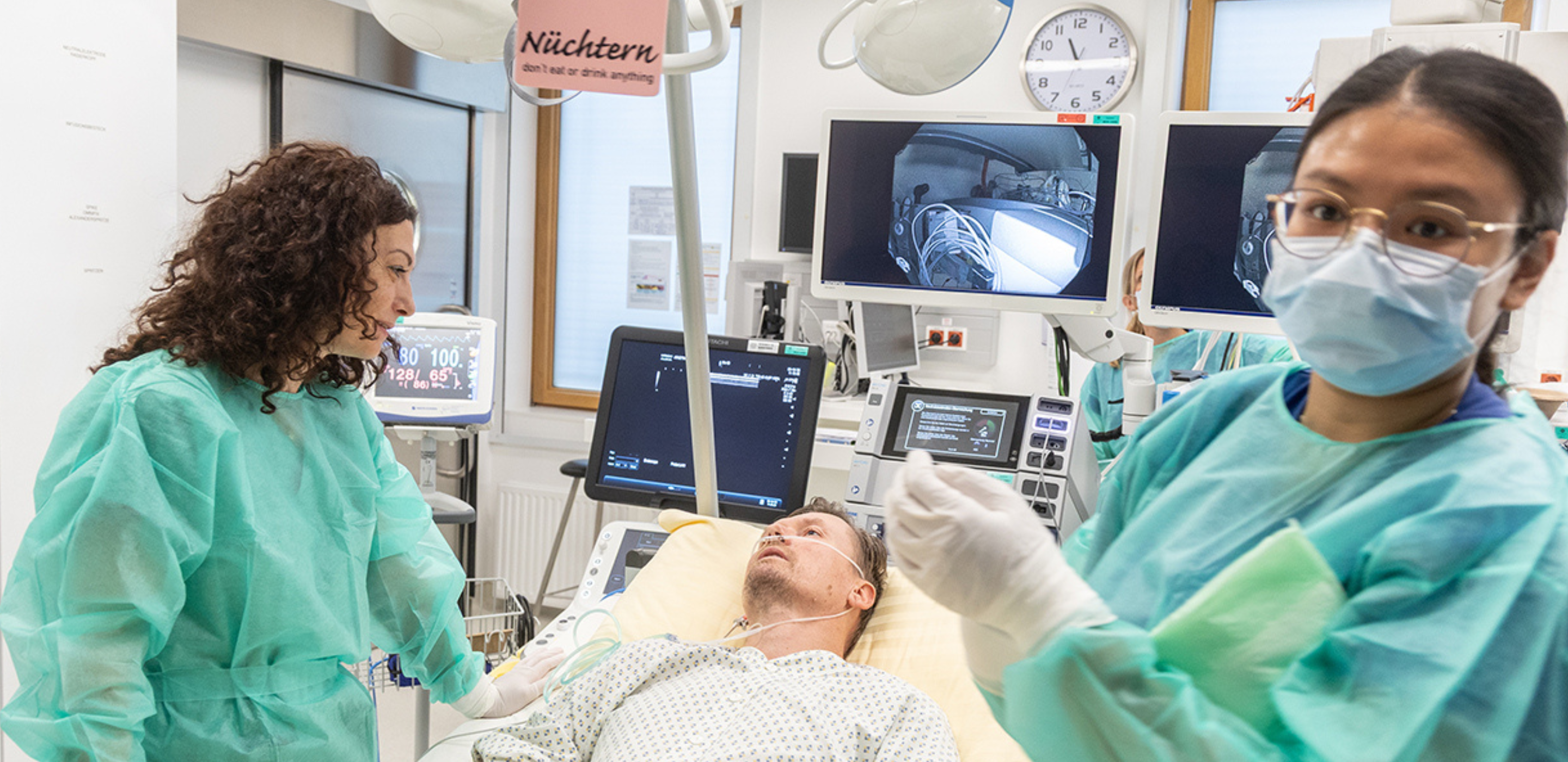 Zwei Ärztinnen mit einem Patienten in einem Behandlungszimmer