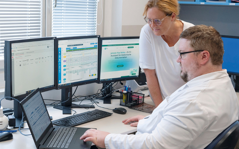 Ärztin und Arzt vor mehreren Bildschirmen