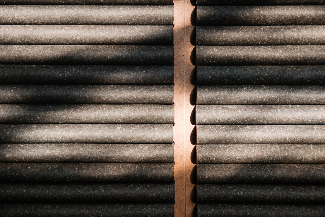Nahaufnahme eines Stapels schwarzer, zylindrischer Objekte mit einem braunen Holzstreifen in der Mitte.