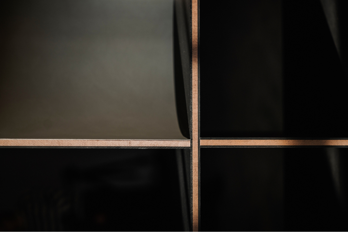Close-up of a black shelving unit with brown wooden dividers and a glass panel on the top shelf.