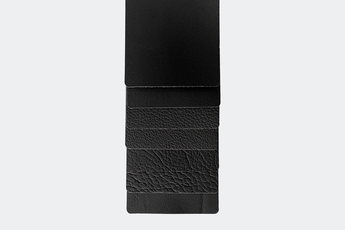 A stack of four black leather sheets, with the top sheet being the largest and the bottom sheet being the smallest.