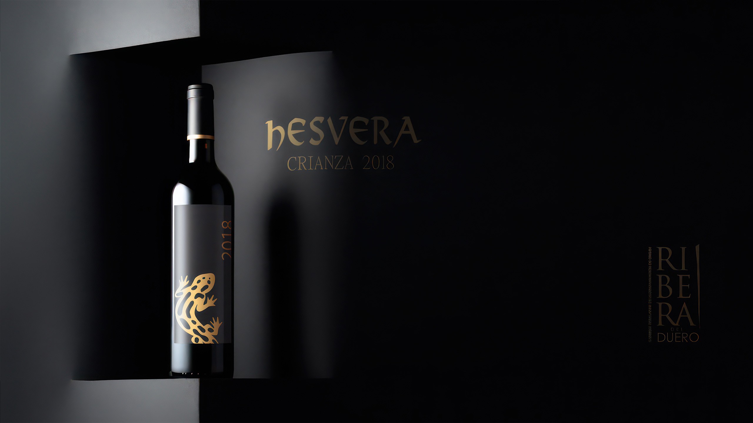 Bottle of Hesvera Crianza 2018 wine with a black label and gold accents, displayed against a black background.