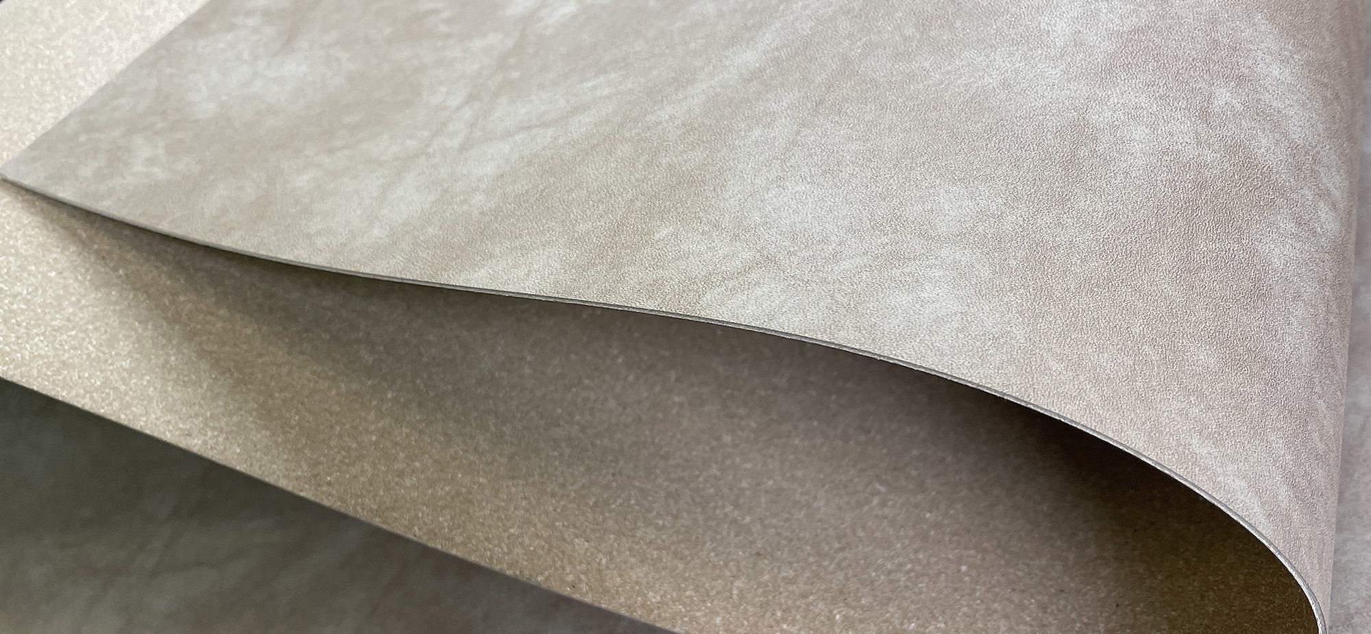 A close-up view of a folded piece of beige fabric with a smooth and shiny surface.