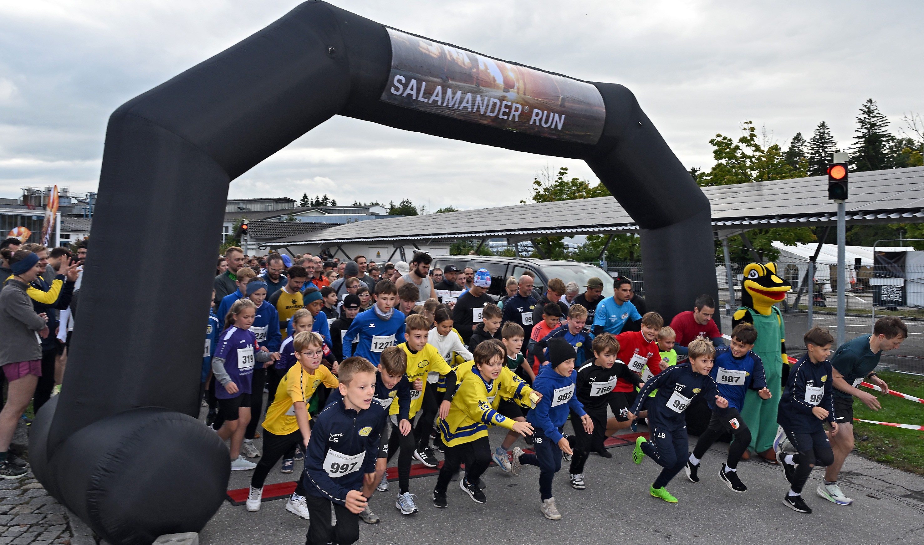 A group of children running in a race with a large inflatable arch in the background that says "Salamander Run".