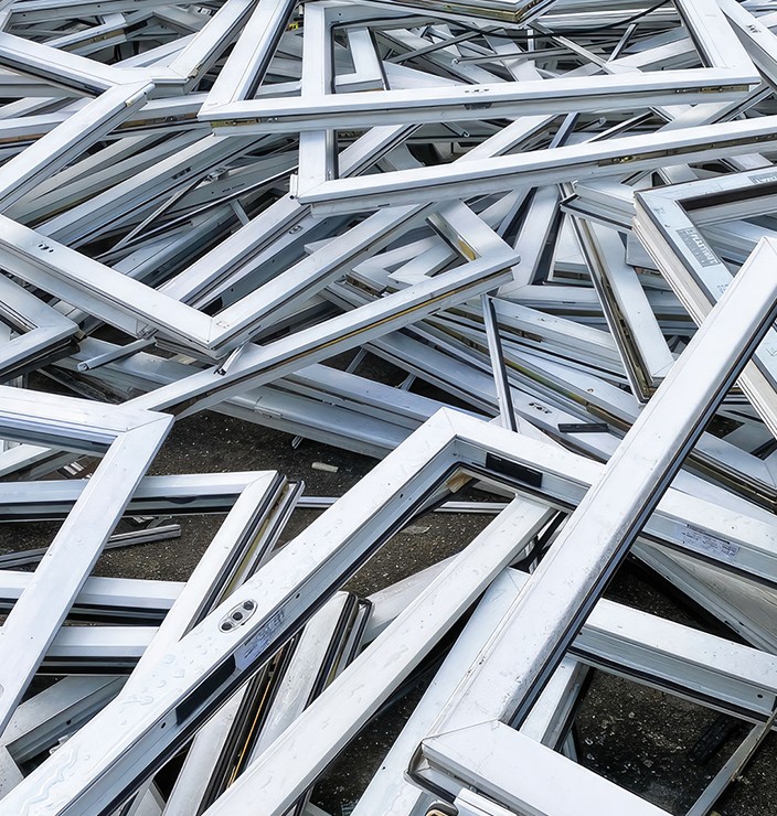 Una pila de marcos de metal blanco, posiblemente de ventanas o puertas, están apilados uno encima del otro.