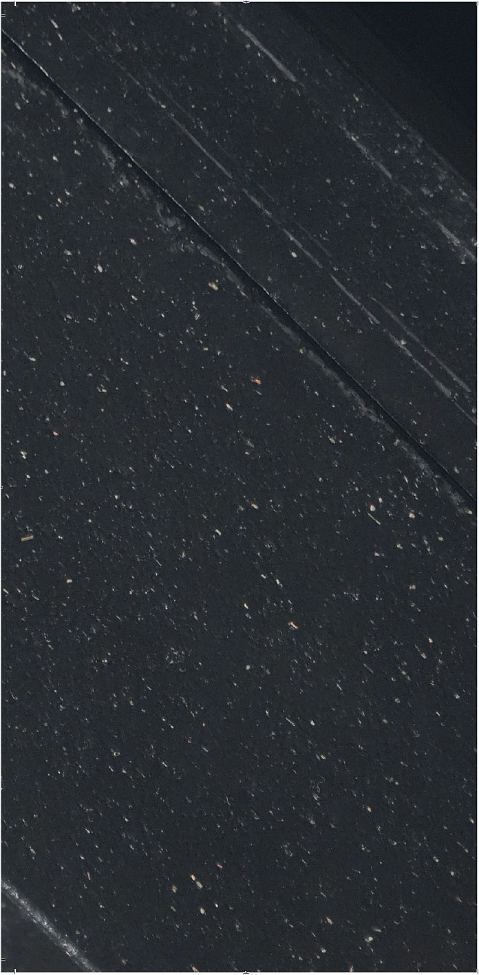 Nahaufnahme einer schwarzen Oberfläche mit einigen weißen Flecken und einer dünnen weißen Linie, die durch sie verläuft.