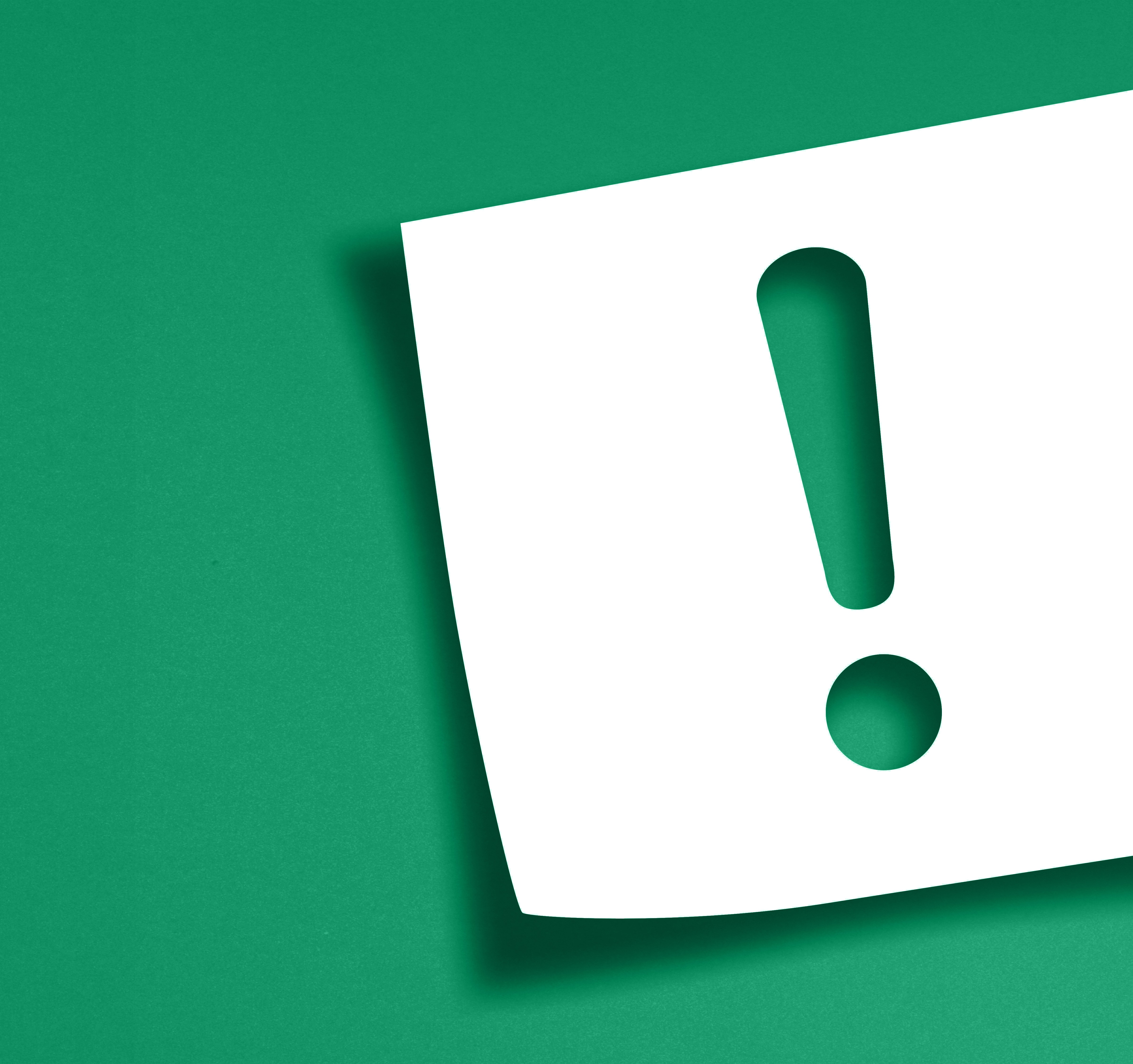 Hârtie albă cu un semn de exclamare pe un fundal verde.
