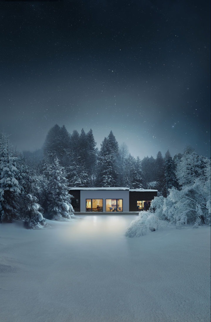 Una casa moderna con grandes ventanas y un techo plano está rodeada de árboles cubiertos de nieve y un cielo nocturno estrellado.