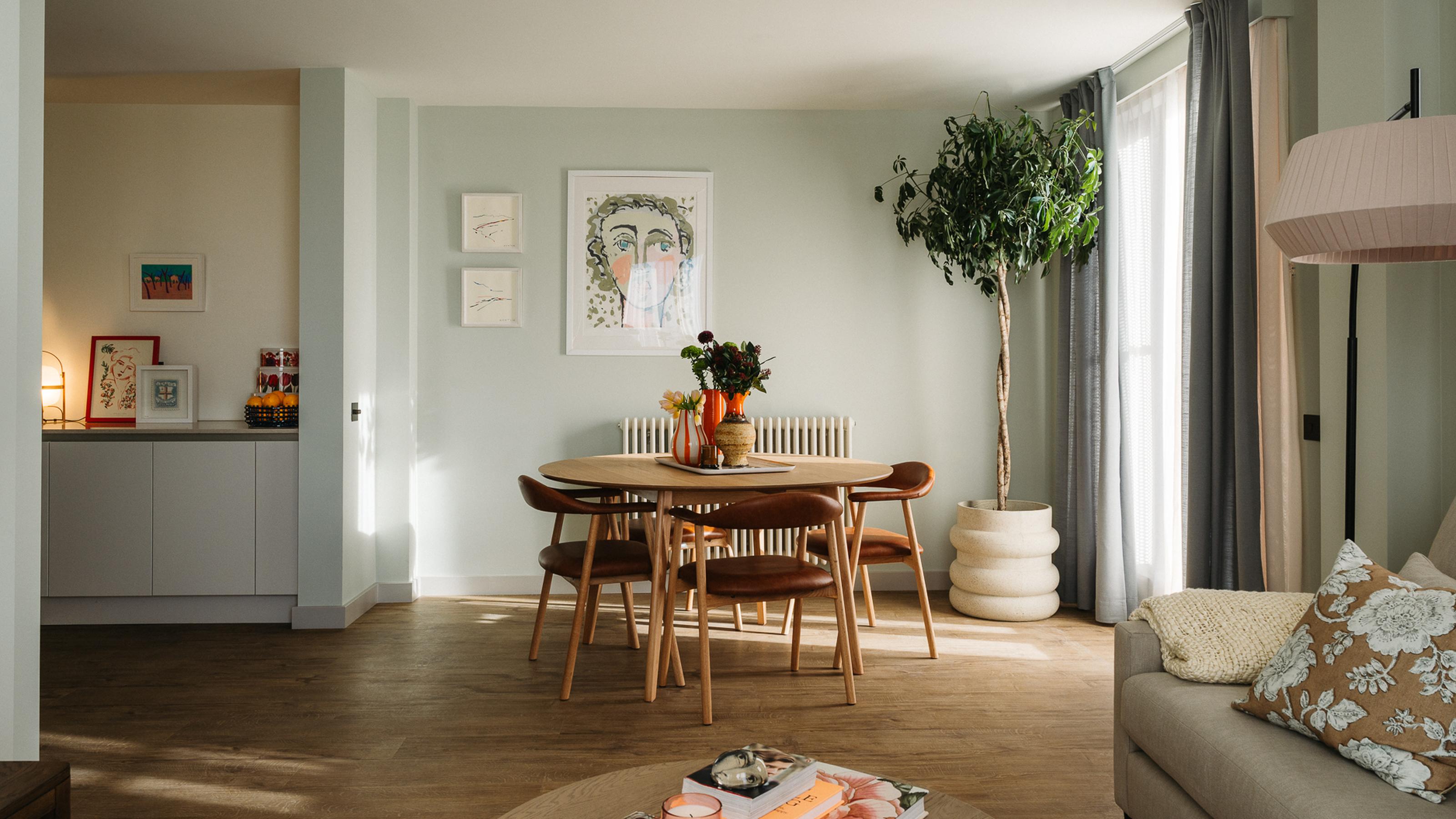 A photo of a dining table adjacent to the lounge and kitchen in an apartment at The Eades.