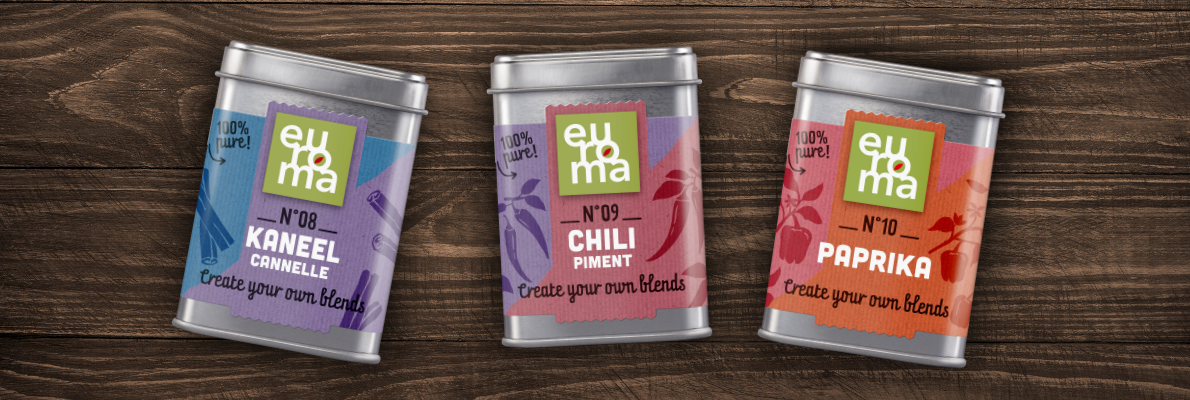 Three colorful Euroma spice tins labeled KANEEL, CHILI, and PAPRIKA on a wooden surface, with “Create your own blends” text.