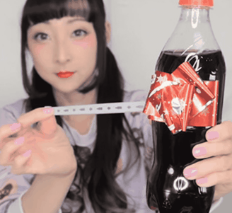 Een  Japanse vrouw houdt een flesje Coca-Cola vast en trekt aan een strookje, waarna een rood label met een feestelijke strik tevoorschijn komt.