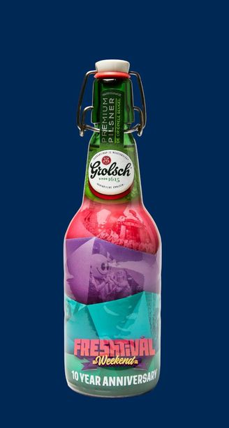 Grolsch beer bottle with colorful festival-themed label reading “Free Festival Weekend 10 Year Anniversary” on a dark blue background