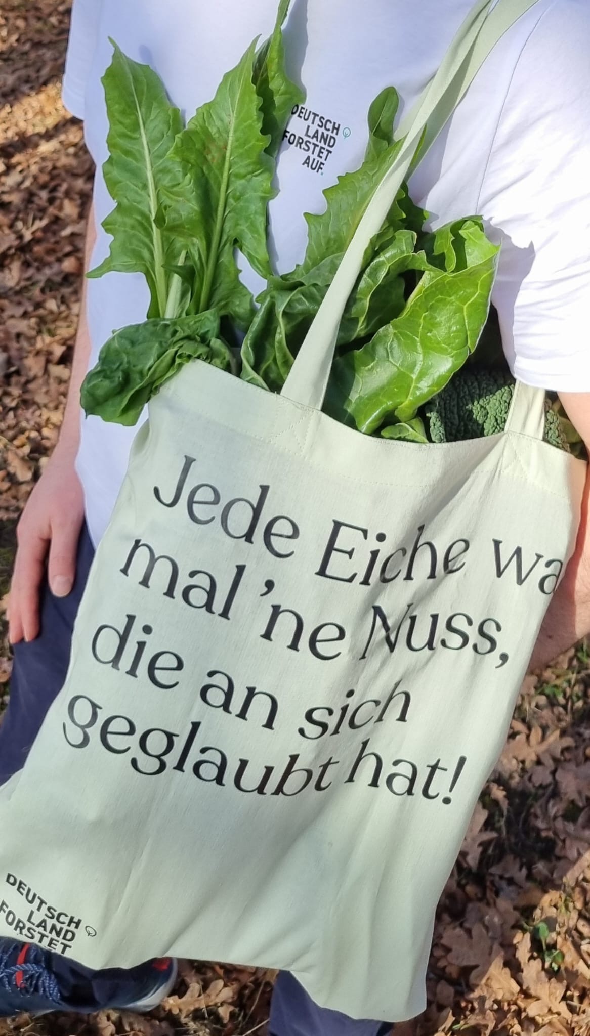 Person mit einer Tragetasche mit Blattgemüse, bedruckt mit einem Deutschland Forstet Auf Text.