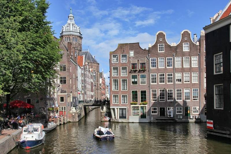 Beeld van een gracht van Amsterdam met een bootje en grachtenpandjes