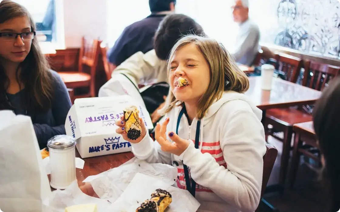 student tasting a cannoli at mike's pastry in boston massachusetts
