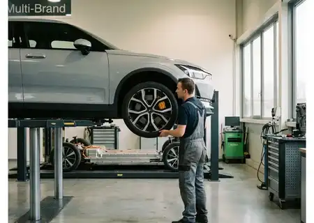 Mechanieker wisselt een wiel van een elektrische auto op de brug in de werkplaats, met op de achtergrond een open batterijplatform van een andere elektrische wagen