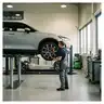 Mechanieker wisselt een wiel van een elektrische auto op de brug in de werkplaats, met op de achtergrond een open batterijplatform van een andere elektrische wagen