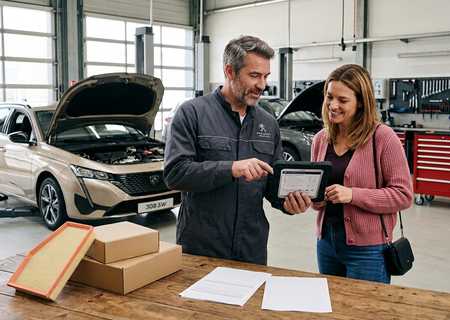 Mechanieker overloopt het onderhoudsplan op een tablet met een klant naast een Peugeot 308 SW in de werkplaats
