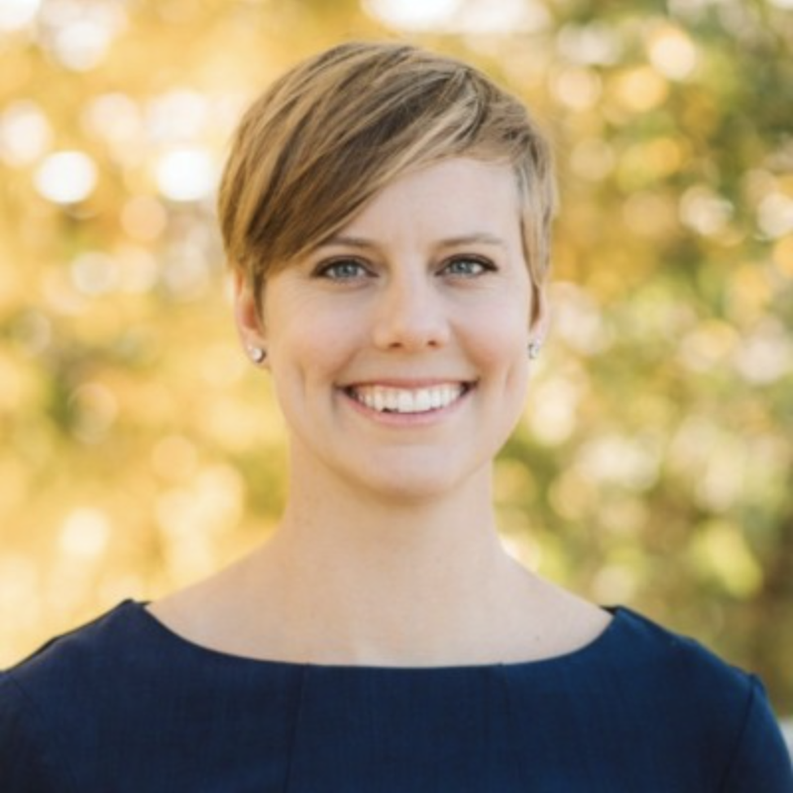 Woman with short hair smiling, wearing a navy blue top