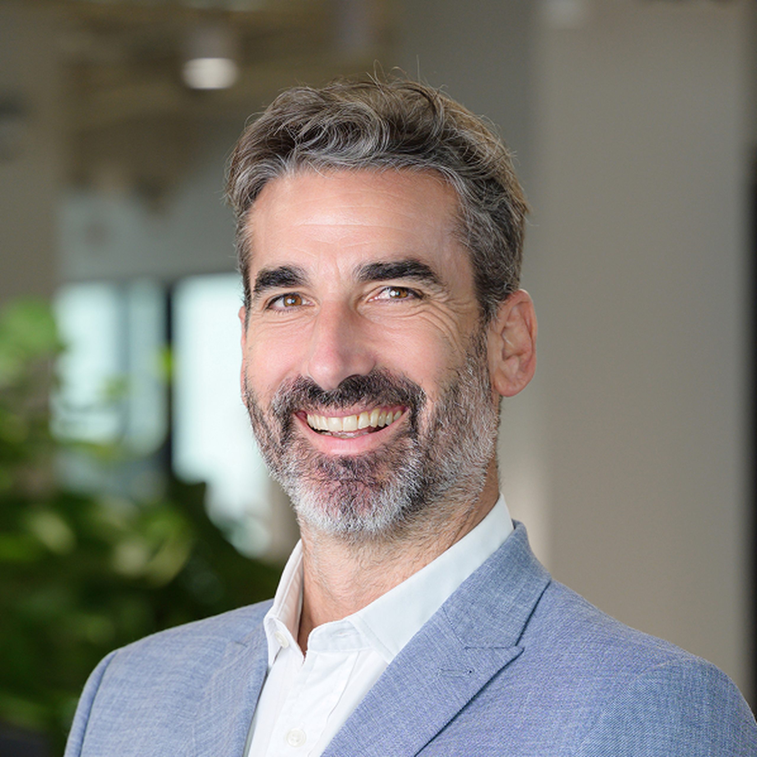 A man with gray hair and a beard smiling