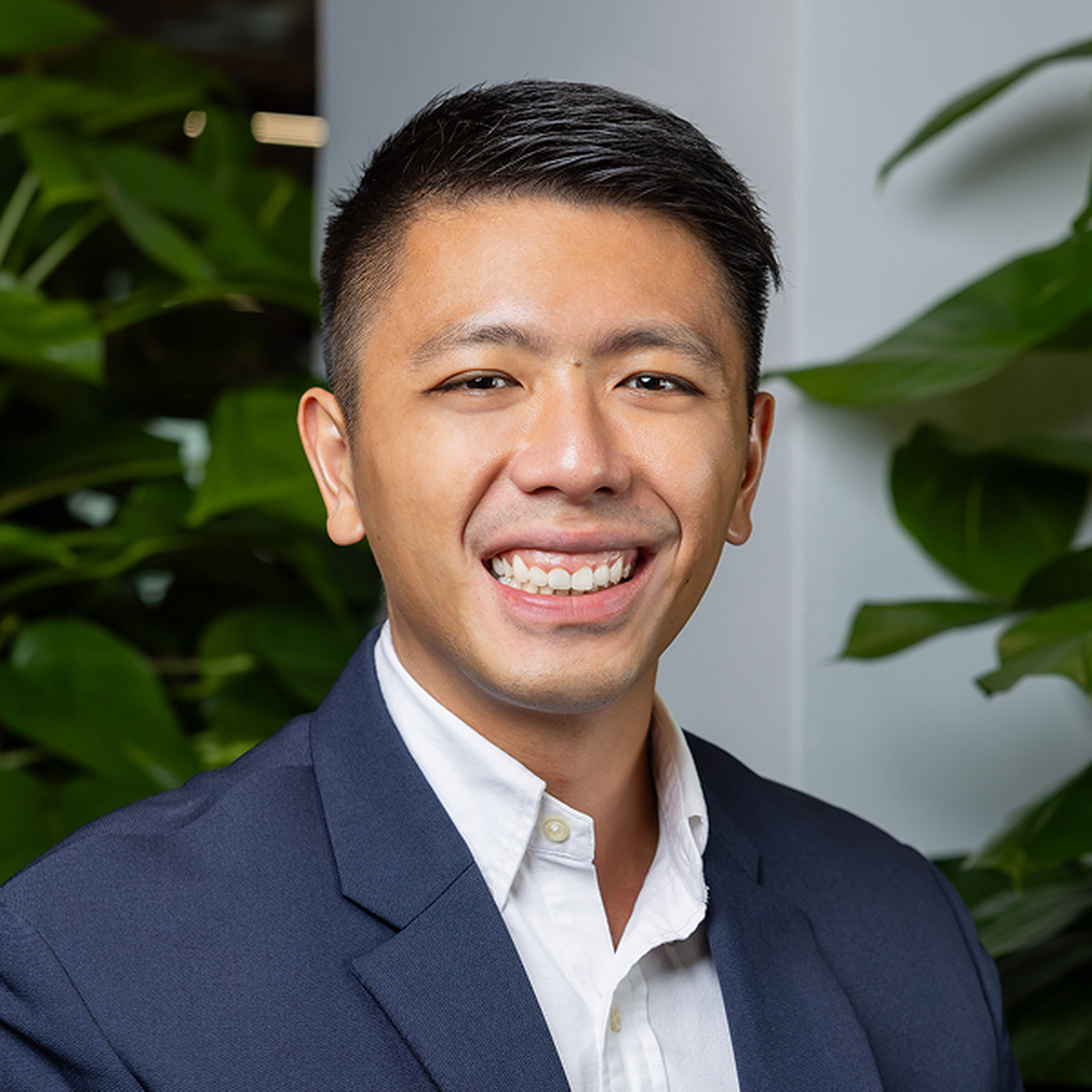 Smiling person with short hair in a dark suit