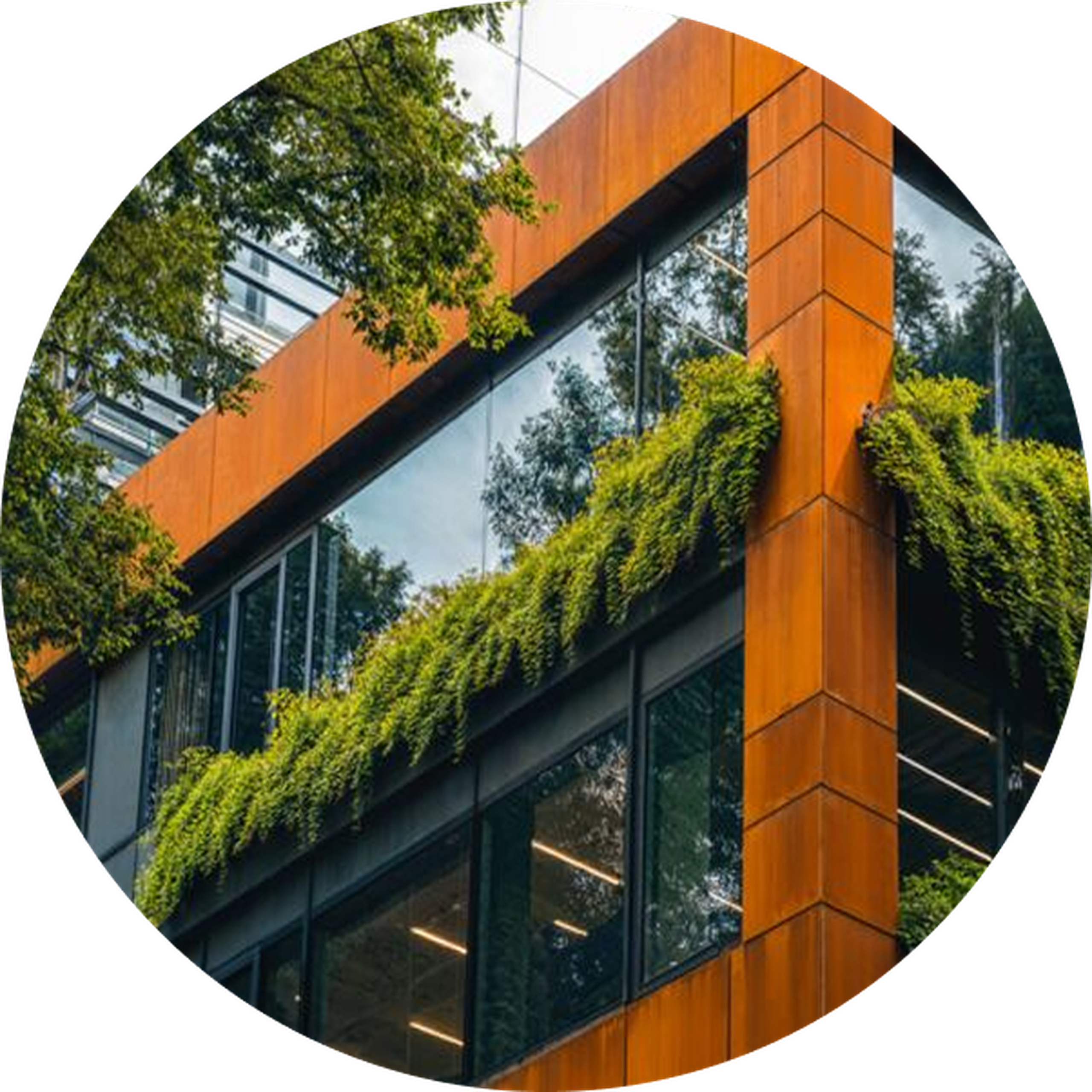Corner view of a modern building with large windows and lush greenery cascading over the orange-brown facade, surrounded by trees.