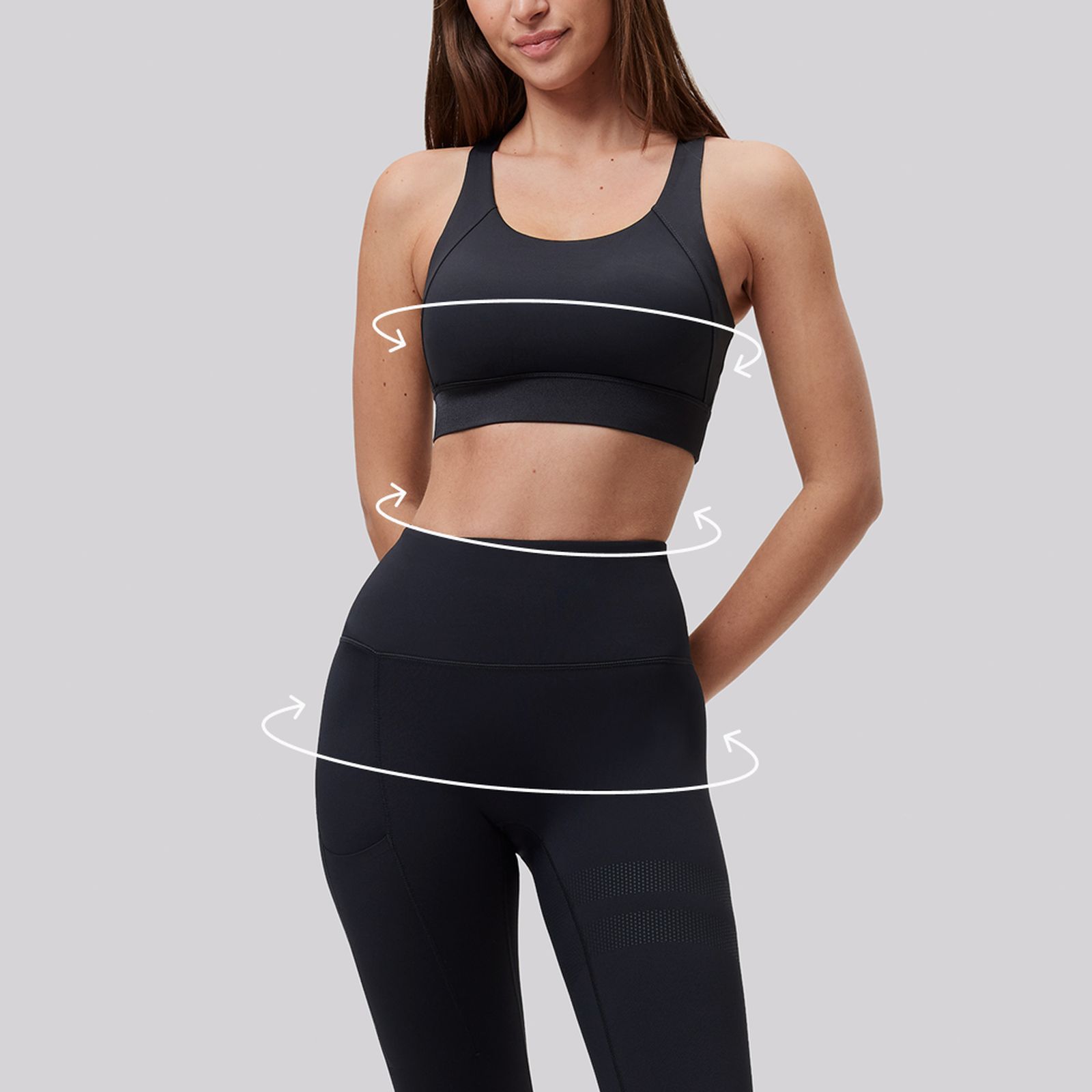 Woman in black sportswear, showing her midriff, with white arrows drawn around her waist and hips, indicating measurement or movement.