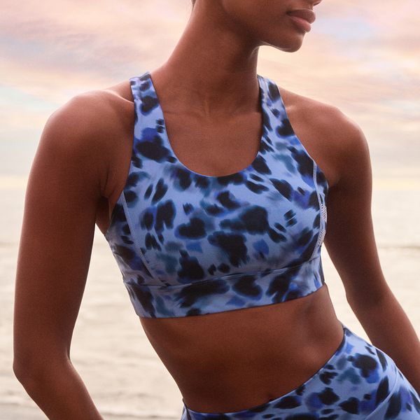 Person wearing a blue and black patterned sports bra, standing outdoors with a sunset sky in the background.