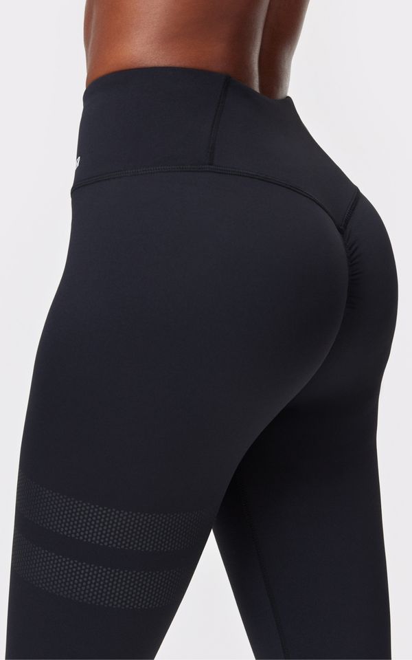 Close-up of a person's lower torso and hips wearing high-waisted black leggings with rear ruching and textured horizontal bands on the thigh.