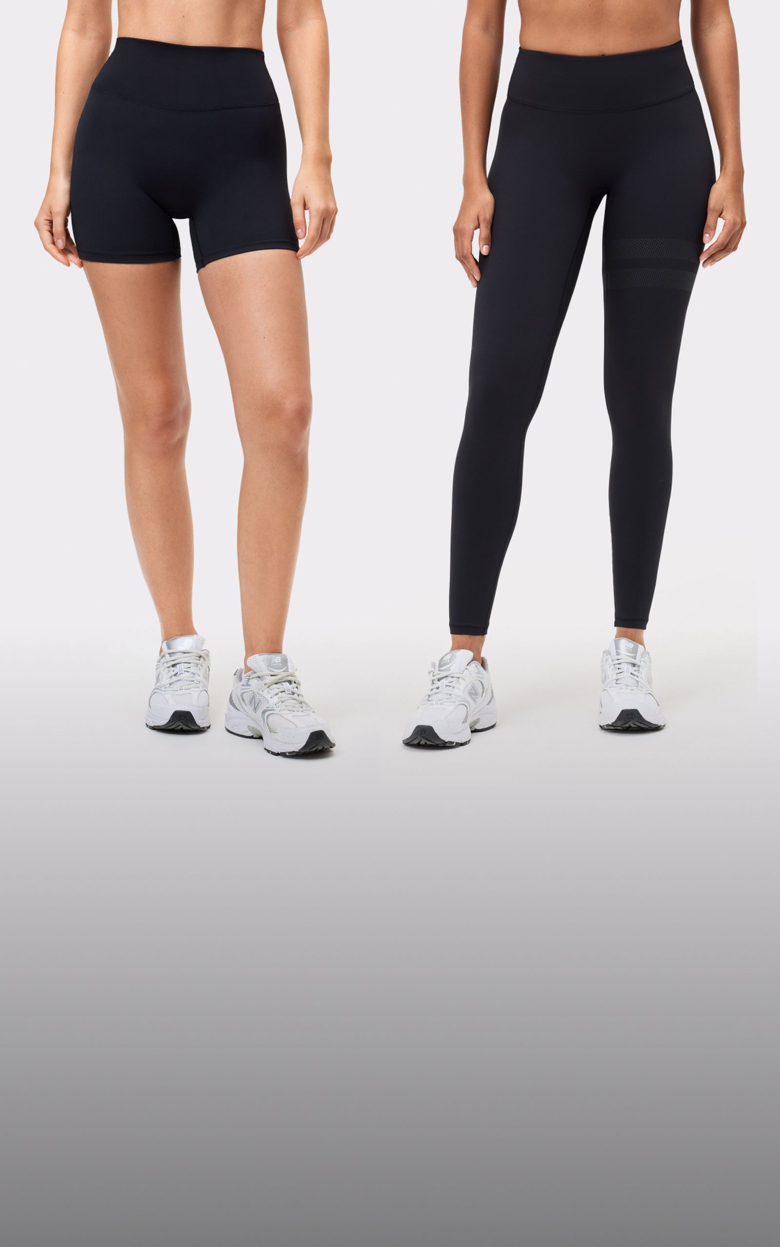 Two people in black activewear, one wearing shorts and the other leggings, both with white athletic shoes against a plain background.