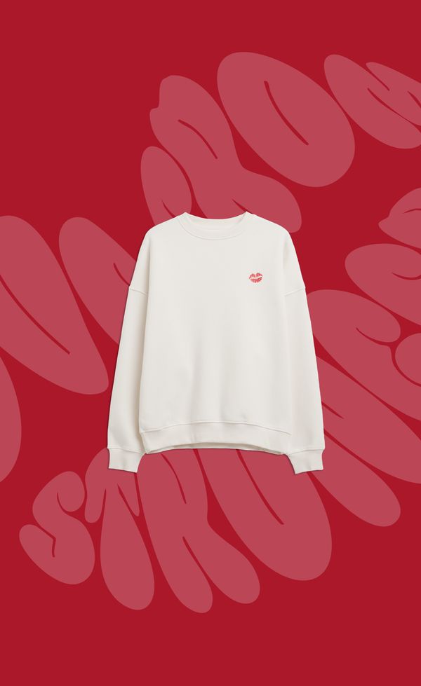 White sweatshirt with a small red logo on the chest, set against a red background with large, distorted text in a darker shade.