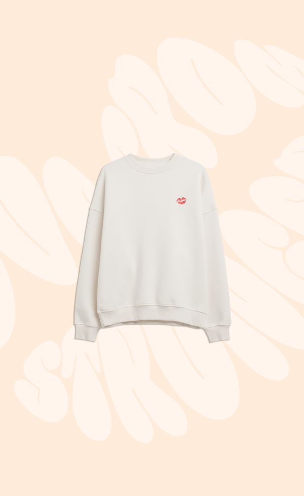 White sweatshirt with a small red apple design on the chest, displayed against a beige background with abstract white shapes.