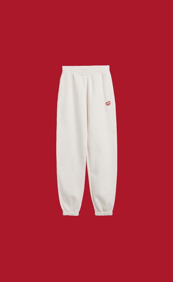 White sweatpants with an elastic waistband and cuffs, featuring a small red logo on the upper left, displayed against a solid red background.