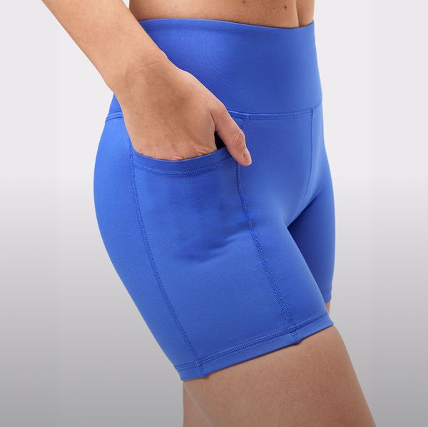 Person wearing bright blue athletic shorts with pockets, close-up of one hand casually in the pocket, against a neutral background.