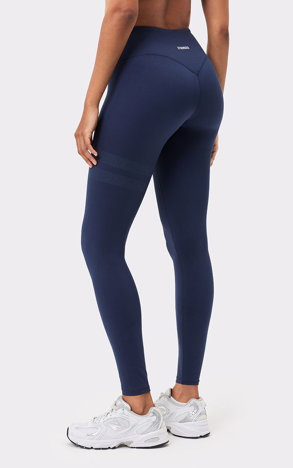 Person wearing navy leggings and white sneakers, viewed from behind against a plain background.