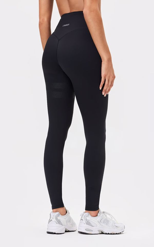 Person wearing black high-waisted leggings and white athletic shoes, viewed from the back against a plain background.