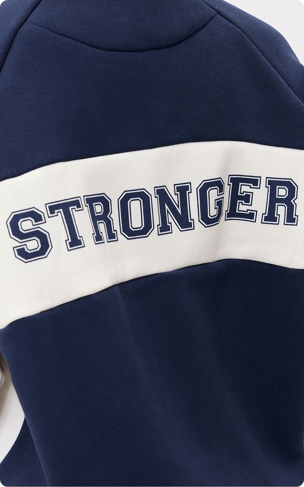 Close-up of a navy and white sweatshirt with the word "STRONGER" printed in bold navy letters on the back.