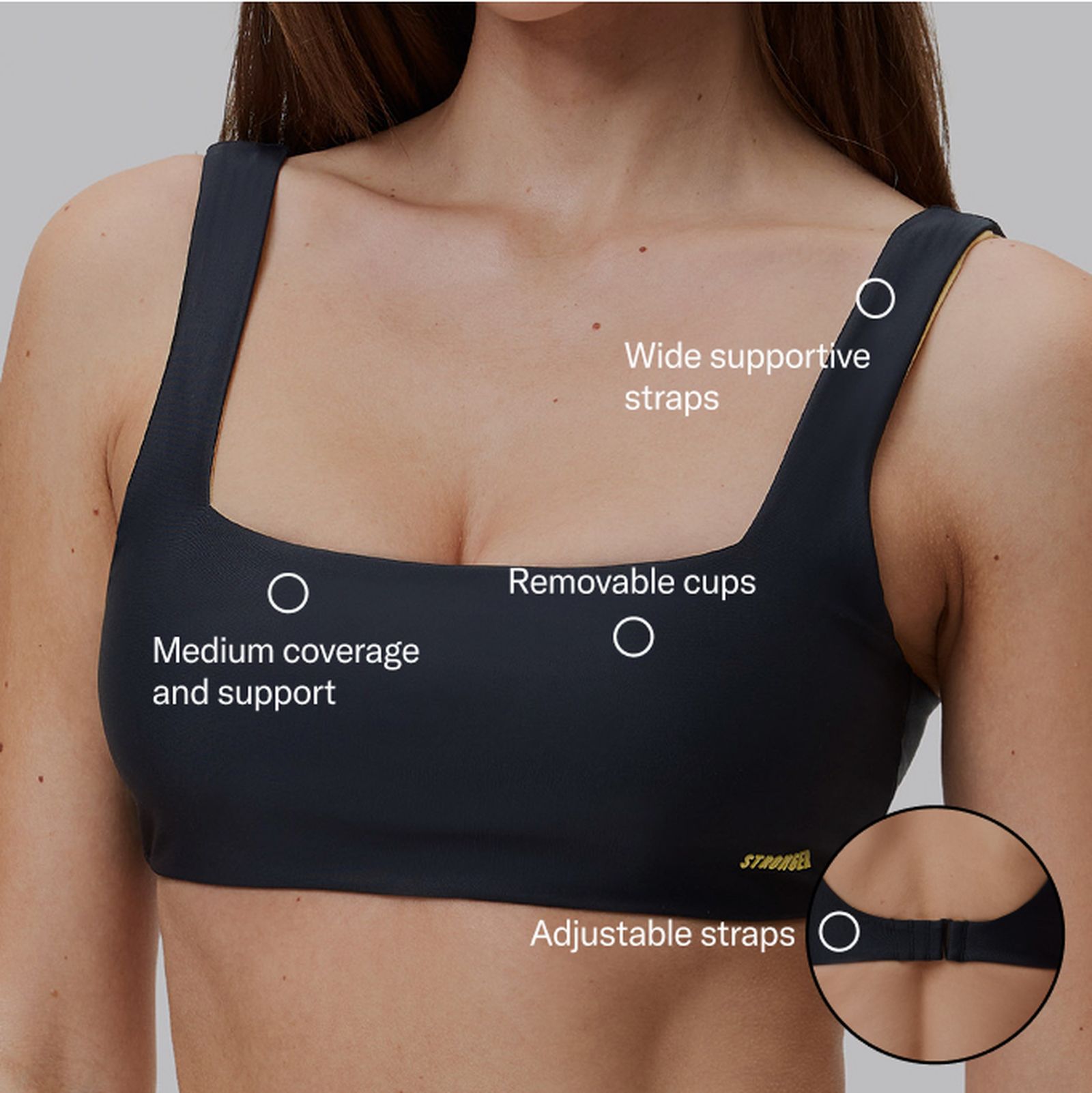 Woman wearing a dark sports bra with wide supportive straps, removable cups, medium coverage, and adjustable straps.