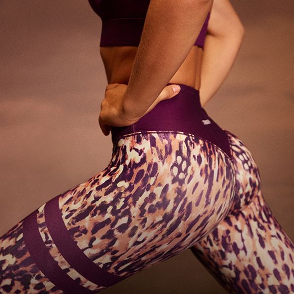 Person wearing leopard print leggings and a purple top, hands on hips, highlighting activewear fashion.