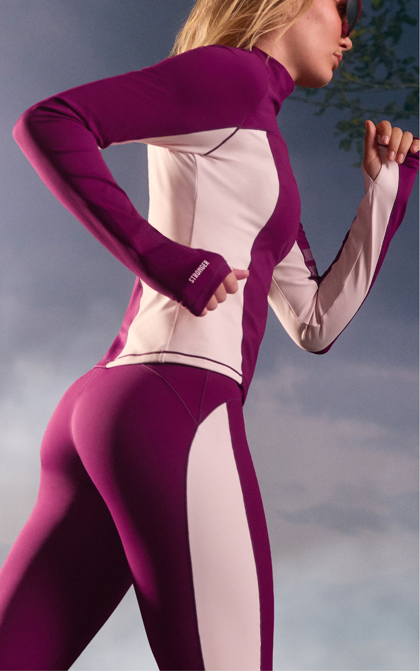 Person running in a purple and white athletic outfit, with overcast sky in the background.