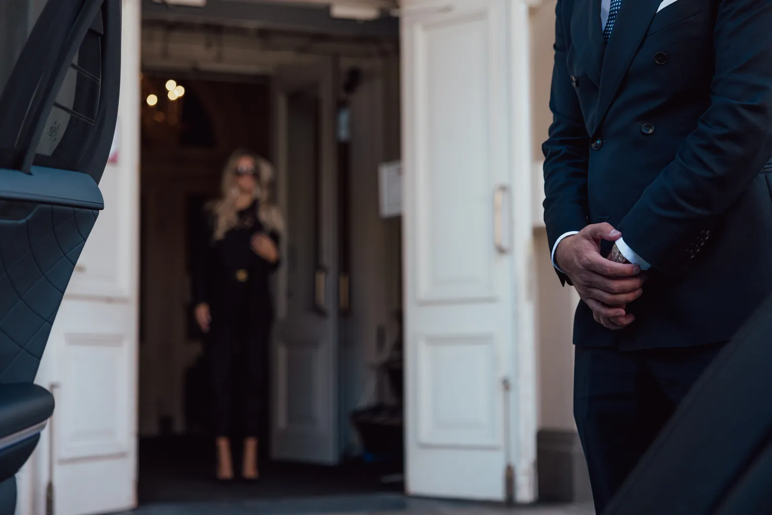 Professional chauffeur in formal attire opening luxury vehicle door