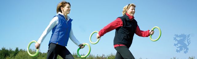 Zwei Frauen gehen mit grünen Ringen in der Natur spazieren