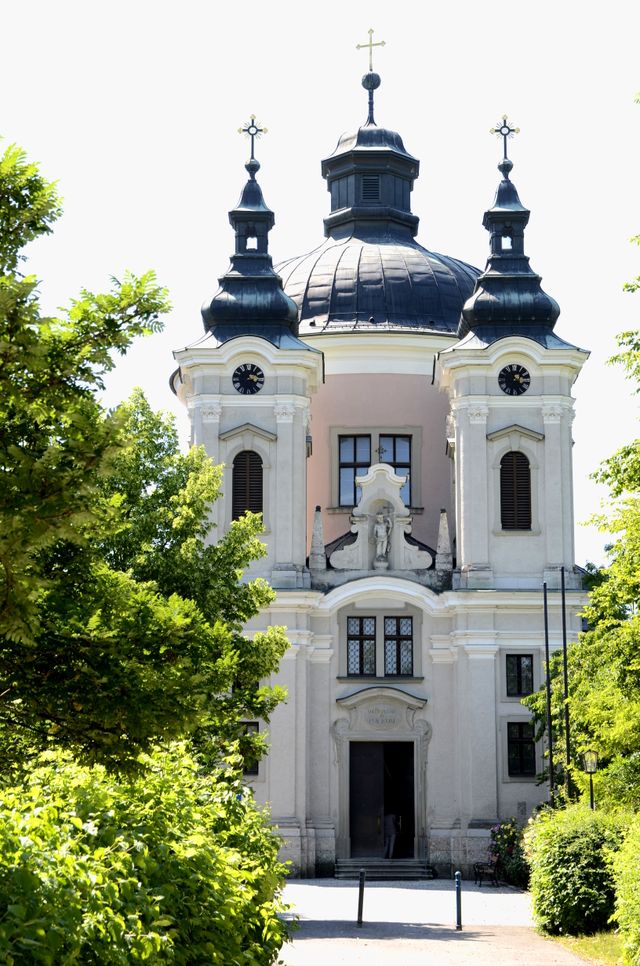 Kirche Christkindl in der Sonne und umgeben vom Grün der Bäume
