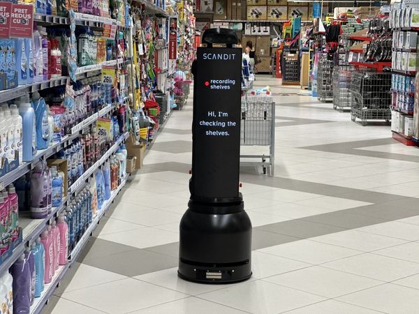 A robot in a store aisle with a display reading, "Hi, I'm checking the shelves," surrounded by household products.