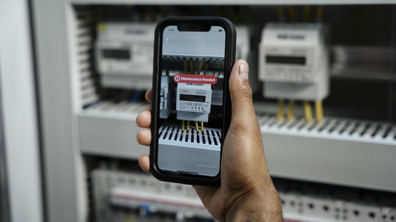 A field service engineer using a data democratization and smart data capture app on an iPhone to identify parts in need of maintenance. 