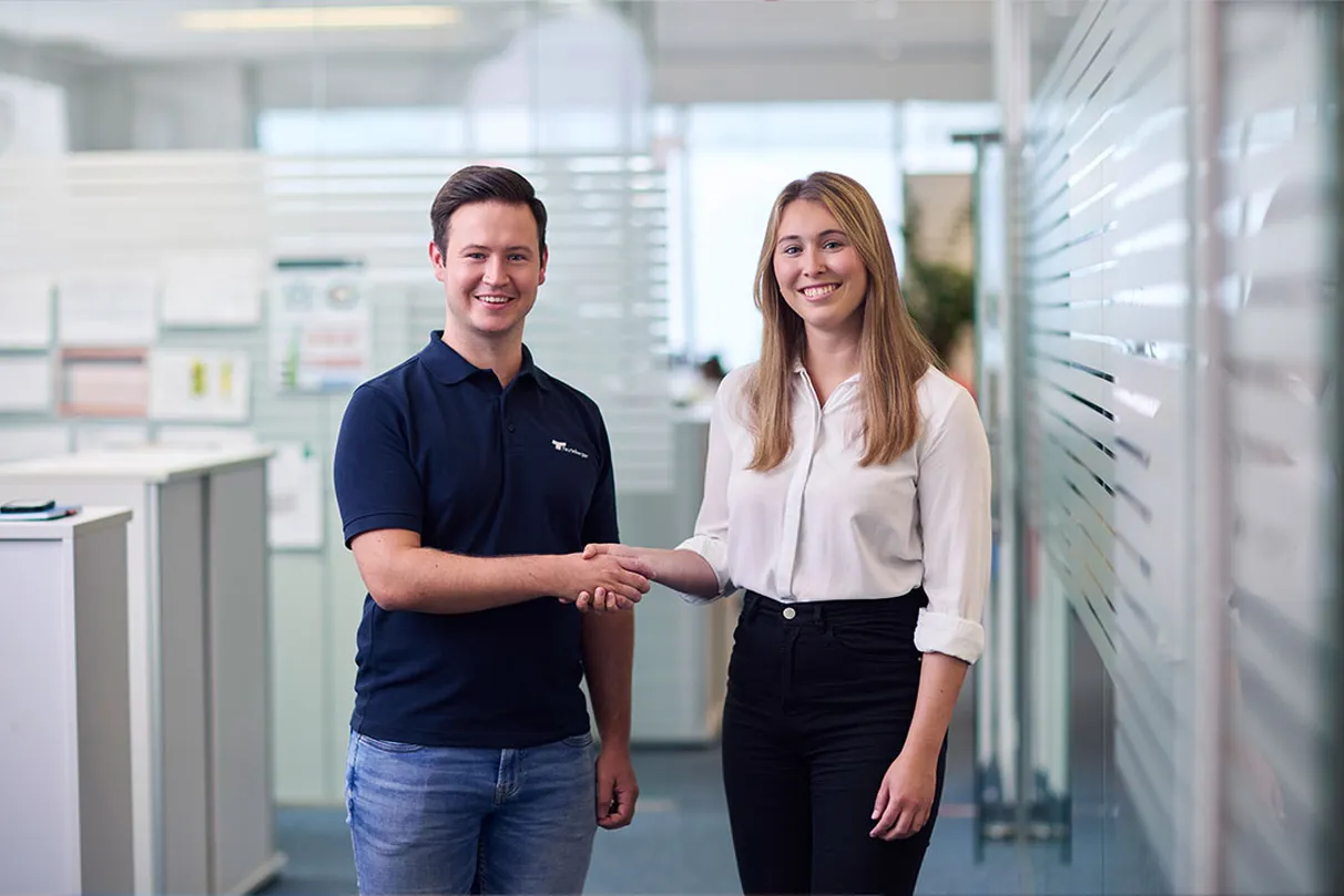 Two people shaking hands in an office environment as a sign of collaboration and trust