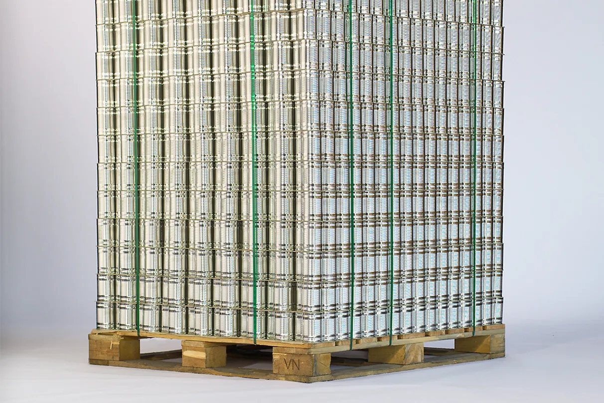 Large stack of metal cans arranged in a grid pattern, secured with green plastic straps, and placed on a wooden pallet.