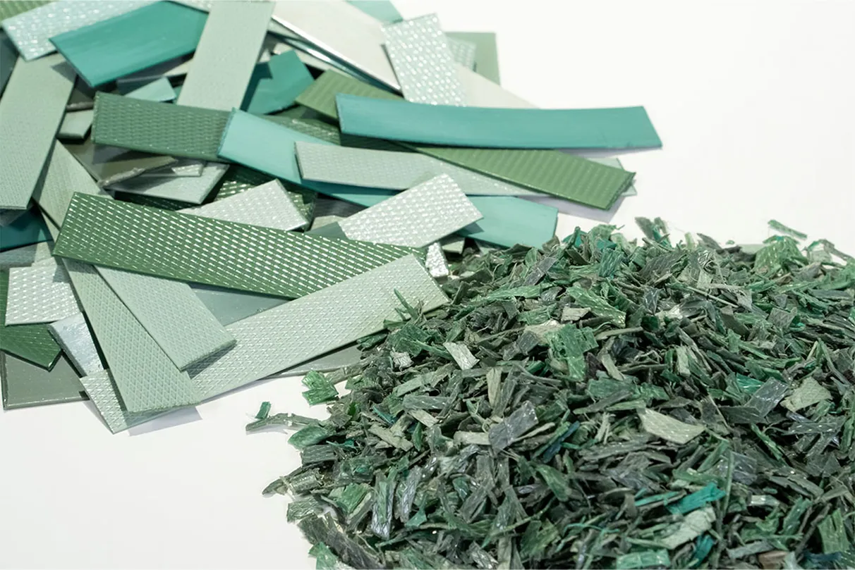Two piles of material side by side – on the left, stacked rectangular strips in green and light blue shades with some textured surfaces; on the right, shredded material in similar green tones.